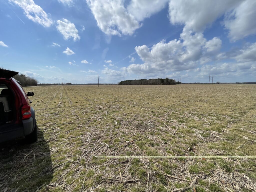 A picture of empty farm land, with a red SUV on the very left hand side. What you cant see is the excited yelling and tears by the new owners